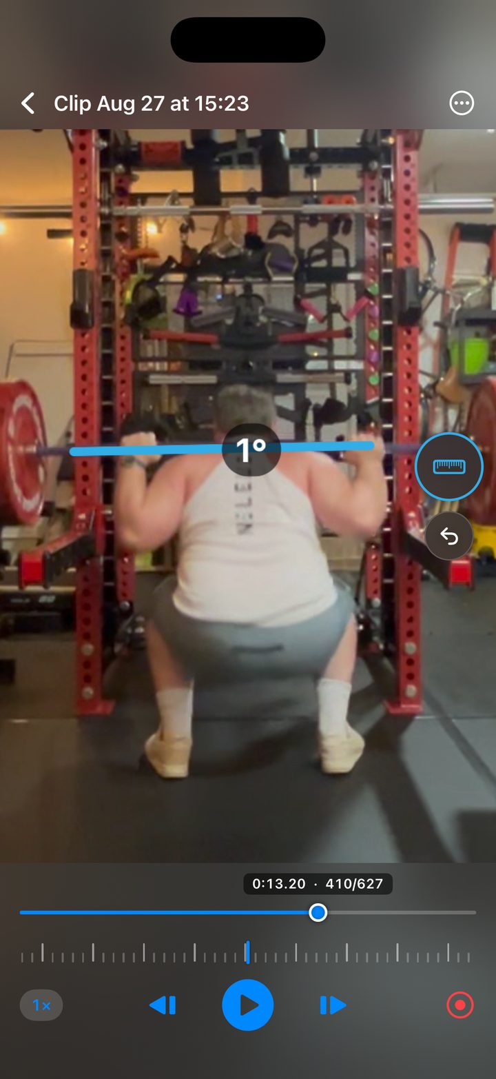 The app mid-analysis: a squat paused on one frame with a joint angle measured across the barbell.